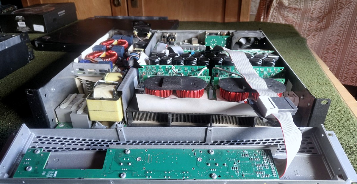 Real user photograph of an opened power amplifier showing circuit boards, capacitors and internal components